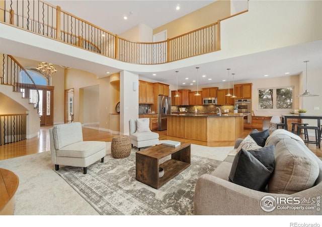 living area featuring light wood-type flooring, a notable chandelier, a wealth of natural light, and recessed lighting