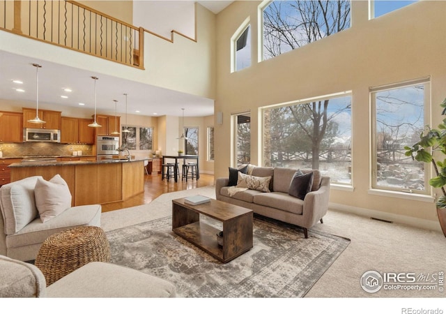 living area with recessed lighting, visible vents, and baseboards