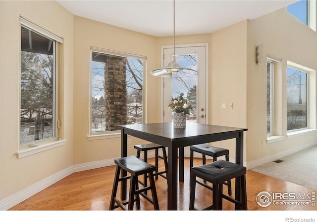 dining space featuring light wood-type flooring, visible vents, and baseboards