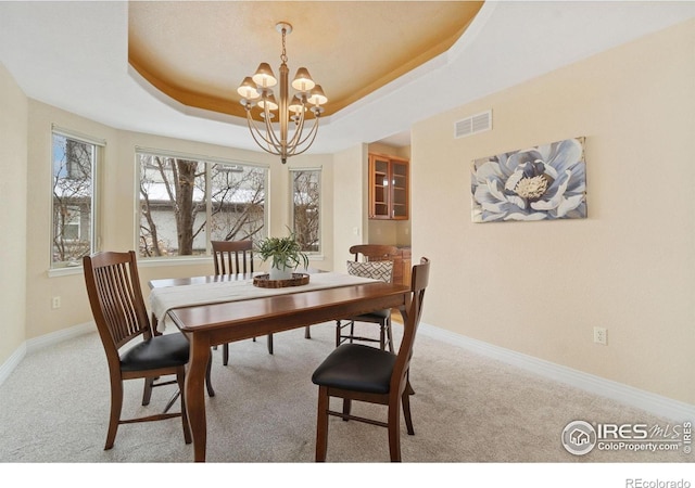 dining area featuring a chandelier, carpet floors, a tray ceiling, and visible vents