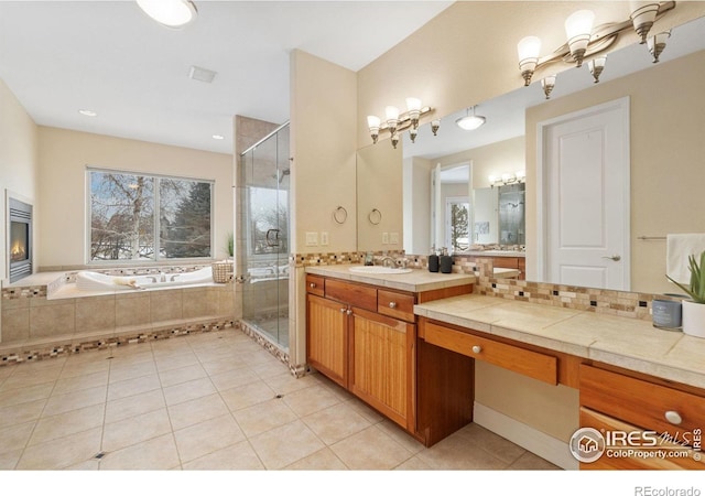 full bath with a shower stall, vanity, a chandelier, and a glass covered fireplace