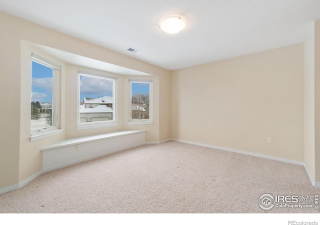 unfurnished room with carpet floors, plenty of natural light, visible vents, and baseboards