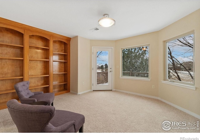 living area featuring baseboards and light colored carpet