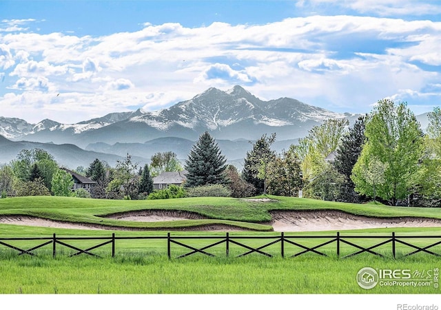 surrounding community featuring a rural view, a mountain view, fence, and a lawn