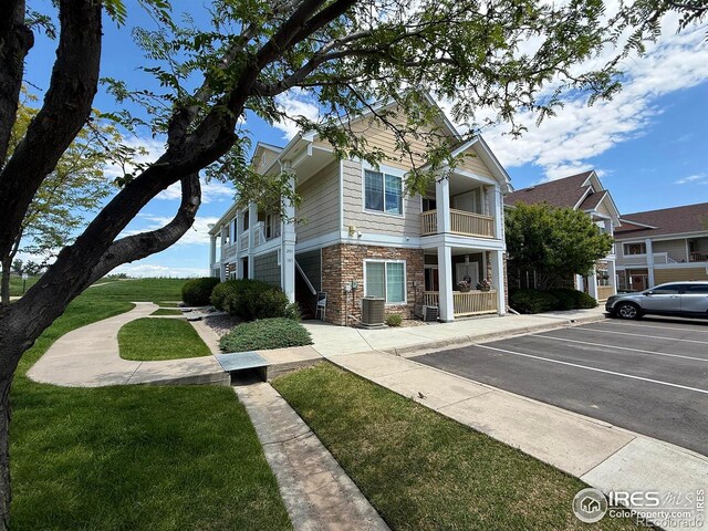 4645 Hahns Peak Dr Unit 201, Loveland, CO 80538 - view of front facade with stone siding, uncovered parking, and a balcony