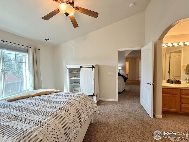 4645 Hahns Peak Dr Unit 201, Loveland, CO 80538 - bedroom featuring light carpet, arched walkways, baseboards, a sink, and ensuite bath