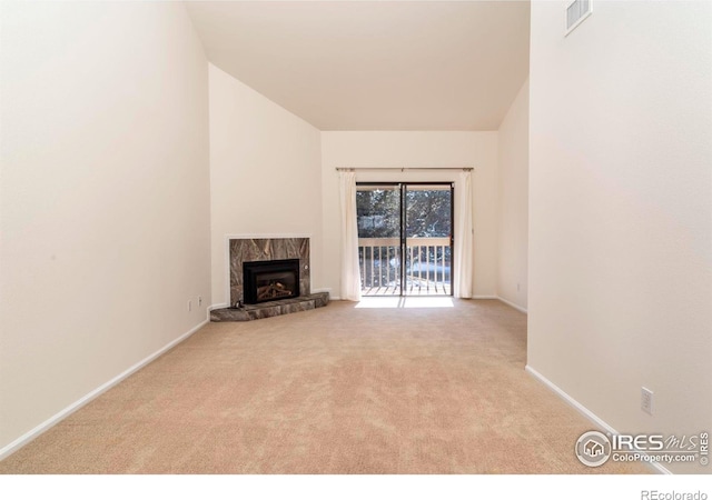 unfurnished living room with light carpet, a high end fireplace, visible vents, and baseboards