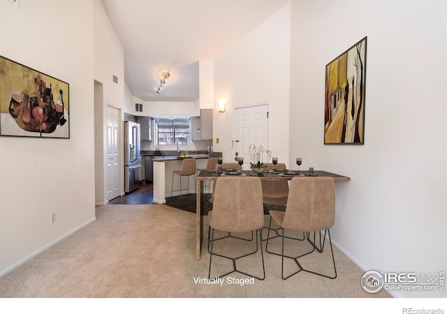 dining space with carpet flooring, baseboards, visible vents, and a towering ceiling
