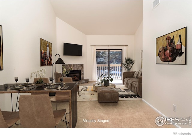 carpeted living room with a high end fireplace, high vaulted ceiling, baseboards, and visible vents