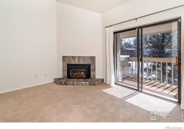 unfurnished living room with carpet floors, baseboards, and a stone fireplace