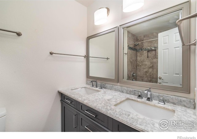 full bath with double vanity, a sink, a shower, and toilet