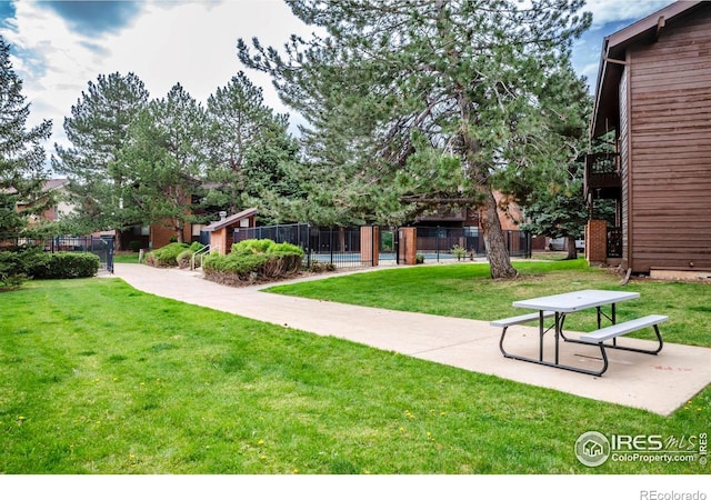 view of community featuring a lawn and fence