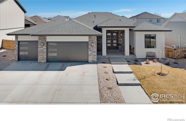 view of front of house featuring a garage, a shingled roof, fence, driveway, and stone siding