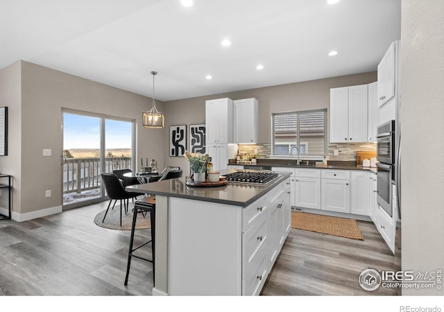 kitchen featuring tasteful backsplash, white cabinets, dark countertops, a kitchen breakfast bar, and pendant lighting