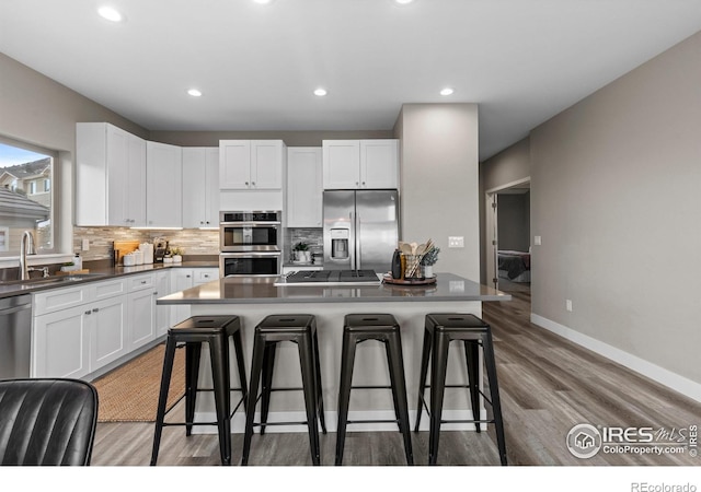 kitchen featuring a center island, white cabinetry, stainless steel appliances, and a kitchen breakfast bar