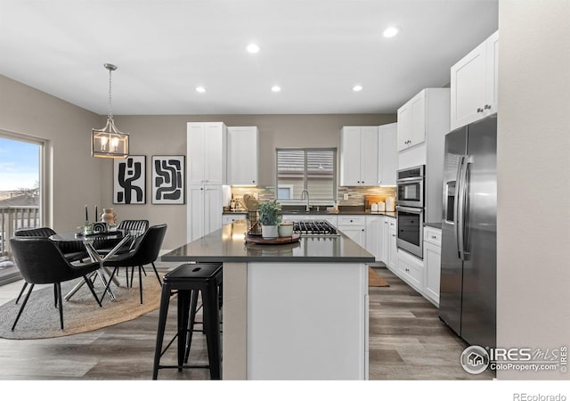 kitchen featuring stainless steel appliances, dark countertops, a center island, and white cabinets