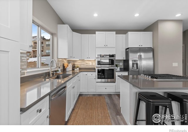 kitchen with stainless steel appliances, dark countertops, white cabinetry, and a breakfast bar area