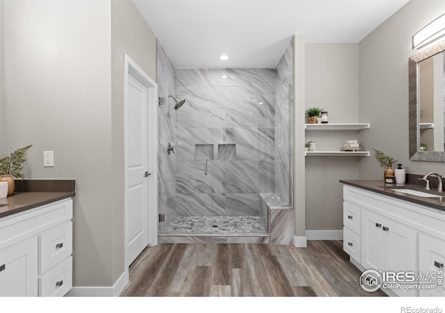 full bathroom featuring a stall shower, vanity, baseboards, and wood finished floors