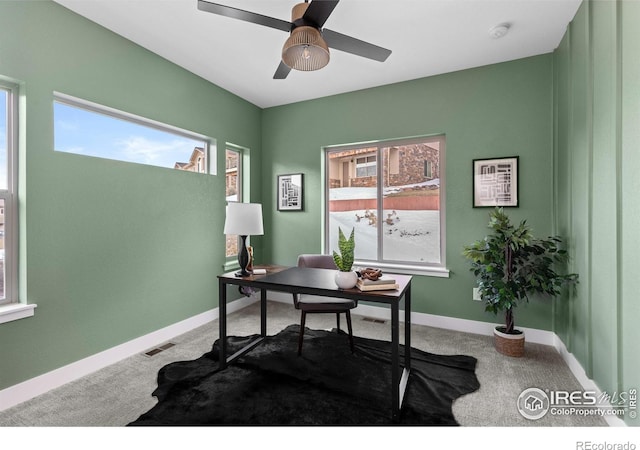 office featuring carpet floors, baseboards, visible vents, and a ceiling fan