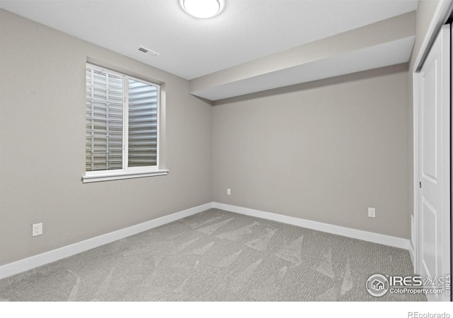 empty room featuring light carpet, visible vents, and baseboards