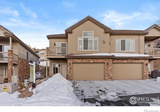 view of property with stone siding, an attached garage, and a balcony