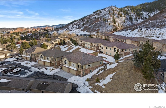 snowy aerial view featuring a residential view and a mountain view