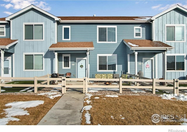 view of front of house featuring a fenced front yard, roof with shingles, and board and batten siding