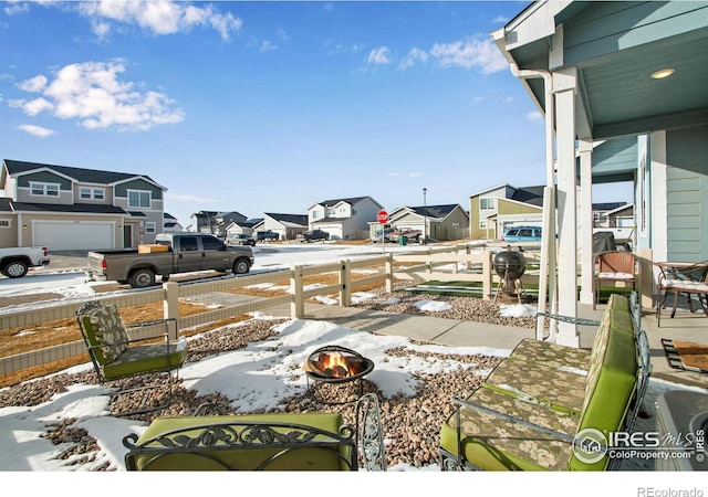 snowy yard featuring a residential view, fence, and a fire pit