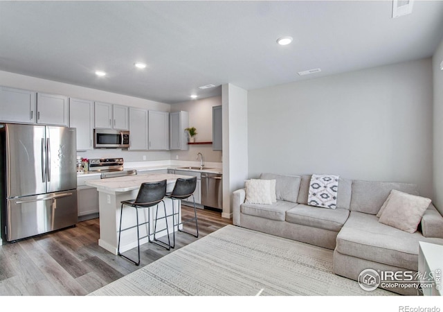 kitchen featuring a center island, appliances with stainless steel finishes, open floor plan, a sink, and a kitchen bar