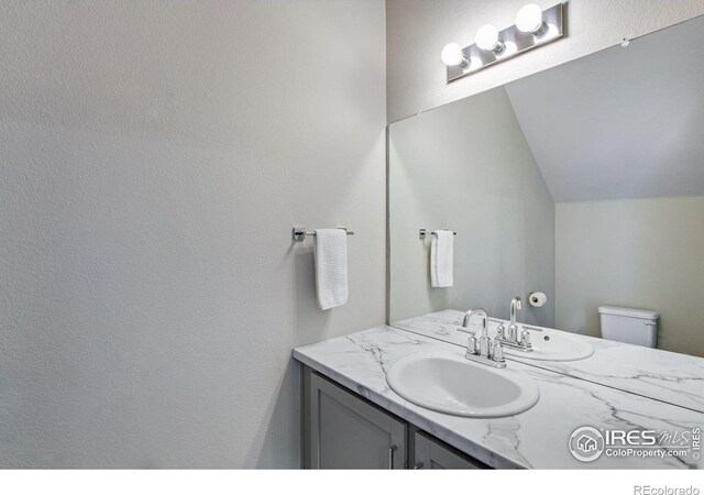 bathroom with lofted ceiling, toilet, and vanity