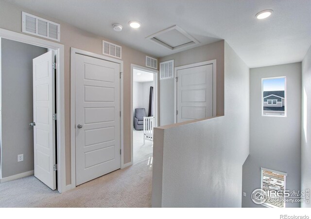 hallway with visible vents and light colored carpet