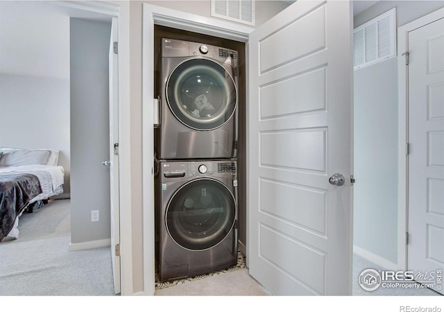 clothes washing area featuring light carpet, laundry area, visible vents, and stacked washer and clothes dryer