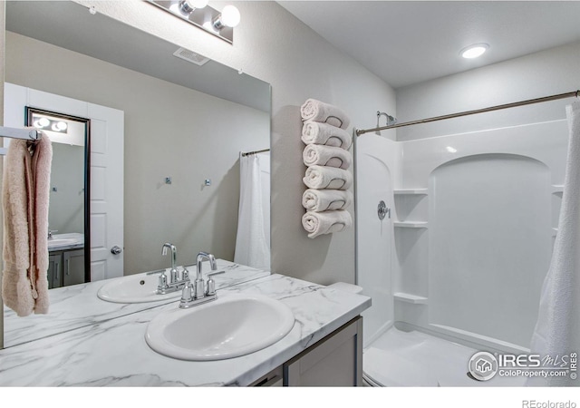 bathroom with curtained shower, visible vents, and vanity