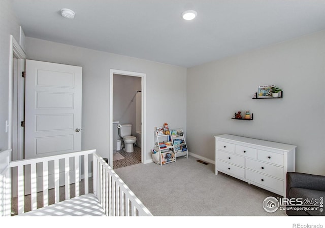 bedroom featuring light carpet, a crib, visible vents, baseboards, and connected bathroom