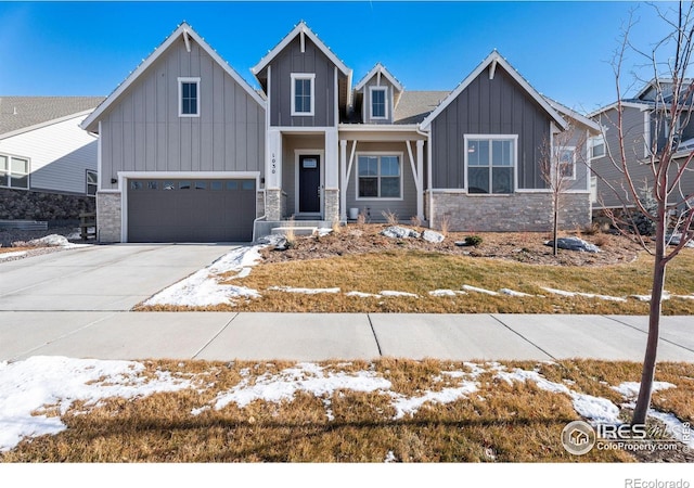 craftsman-style home with a garage, concrete driveway, board and batten siding, and stone siding