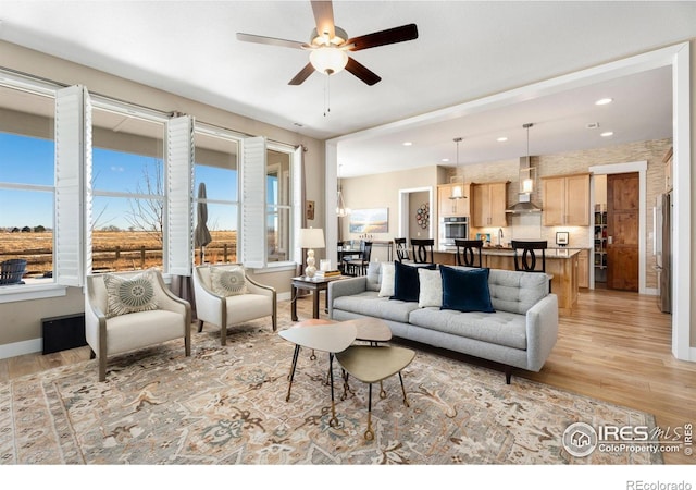 living area featuring ceiling fan, recessed lighting, light wood-style flooring, and baseboards