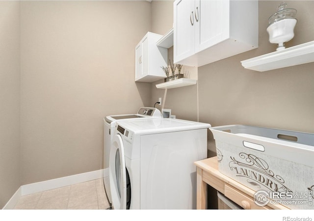 clothes washing area with light tile patterned floors, washing machine and clothes dryer, cabinet space, and baseboards