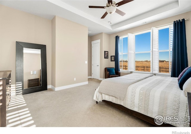 bedroom featuring a raised ceiling, light colored carpet, visible vents, and baseboards