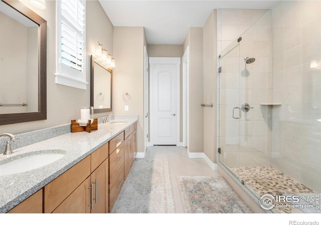 bathroom featuring double vanity, a stall shower, baseboards, and a sink