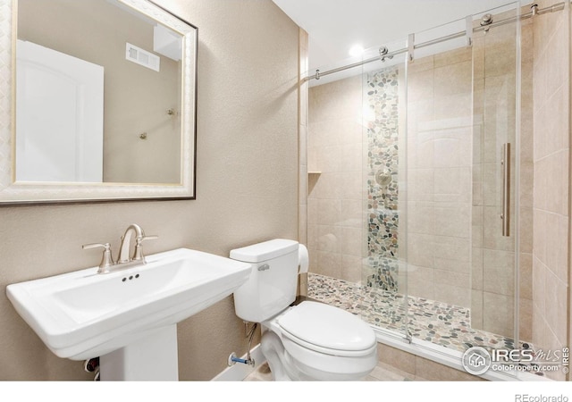 bathroom featuring a stall shower, visible vents, a sink, and toilet