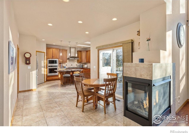 dining area featuring baseboards, light tile patterned floors, a fireplace, and recessed lighting