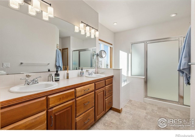 bathroom with a stall shower, double vanity, a sink, and a bath