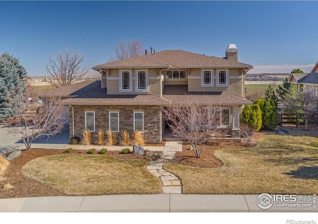 view of front of home with stone siding, a chimney, a front lawn, and stucco siding