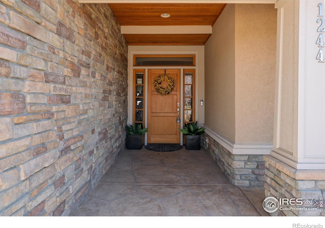 view of exterior entry featuring stone siding and stucco siding