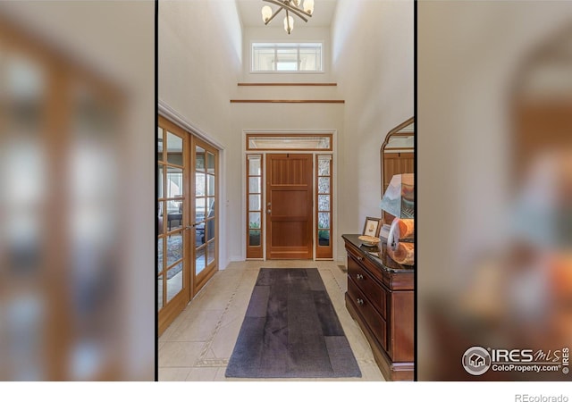 foyer entrance with a high ceiling, a notable chandelier, and french doors