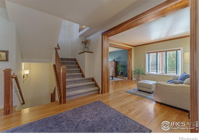 living room with light wood-style floors, ornamental molding, and stairway