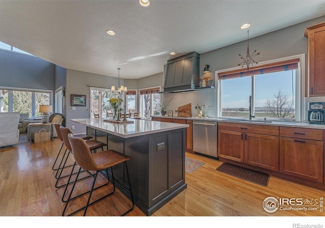 kitchen with a center island, pendant lighting, brown cabinets, light countertops, and dishwasher