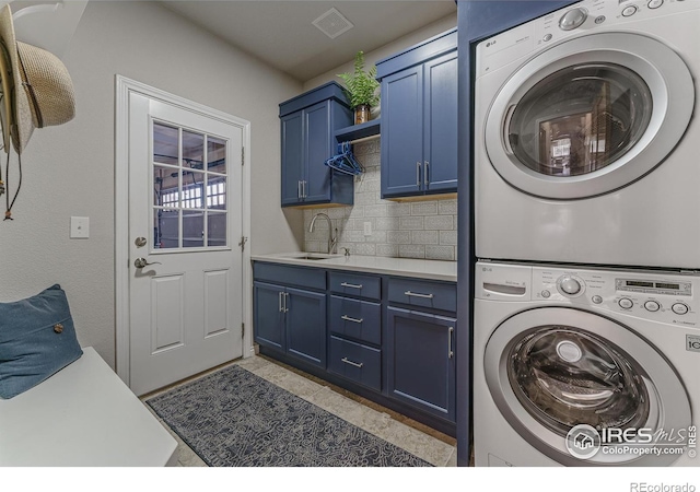 washroom with stacked washing maching and dryer, cabinet space, visible vents, and a sink