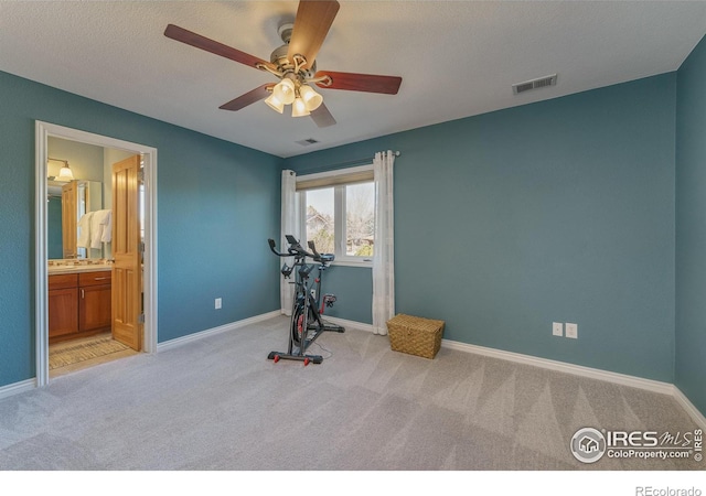 exercise area featuring visible vents, light carpet, and baseboards