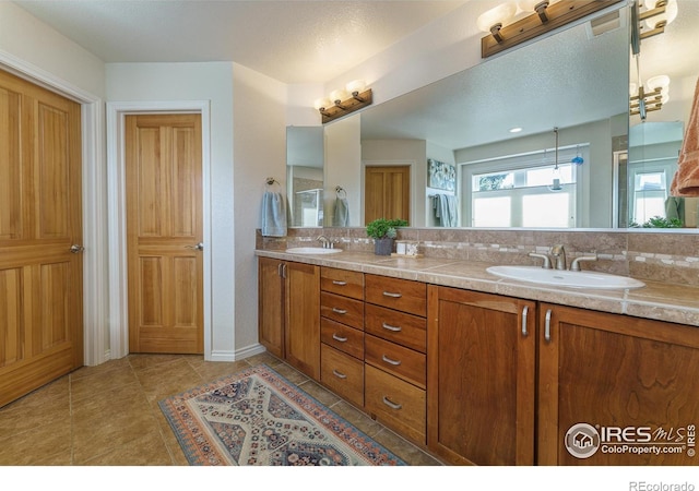 bathroom featuring double vanity, tile patterned flooring, decorative backsplash, and a sink